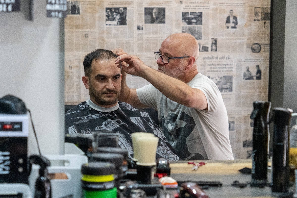 Julio perfilando un corte de tijera, reflejado en el espejo