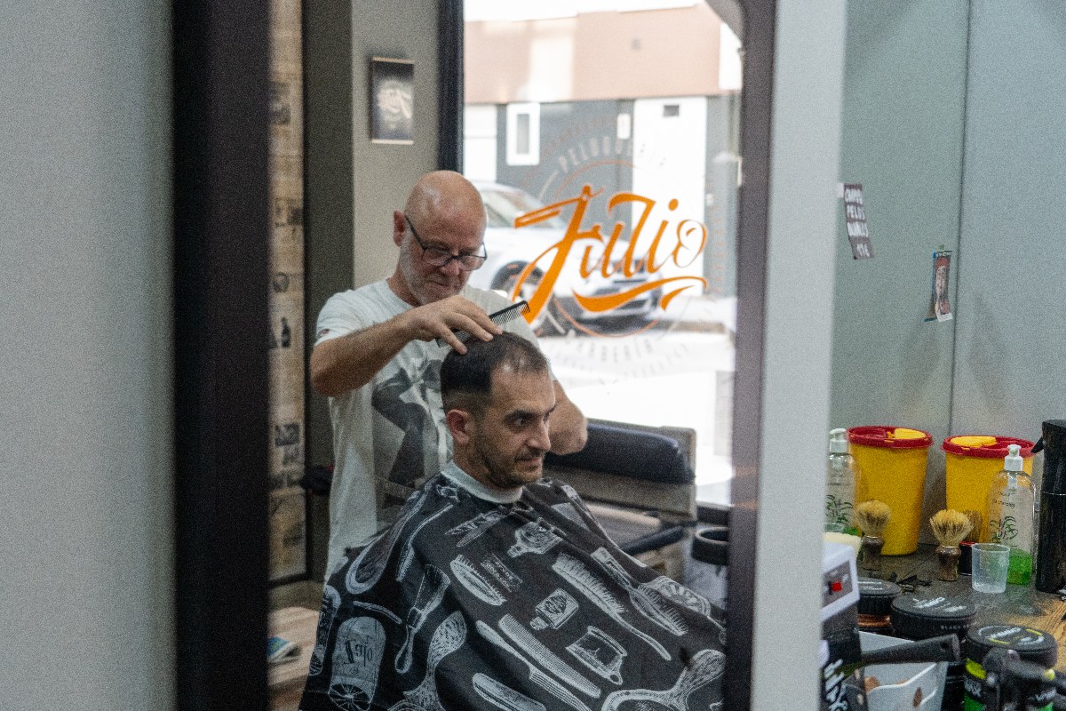 Peinado con peine tras el corte, con el rótulo de la barbería al fondo